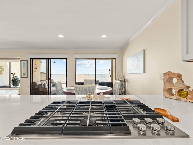 interior space featuring stainless steel gas cooktop, light stone counters, and ornamental molding