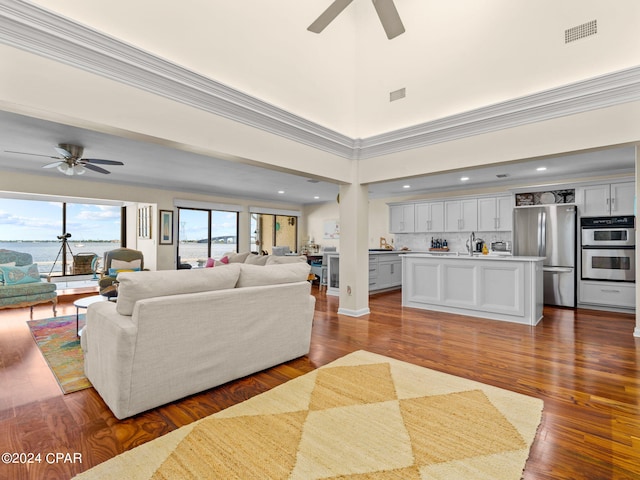 living room featuring crown molding, wood-type flooring, sink, and ceiling fan