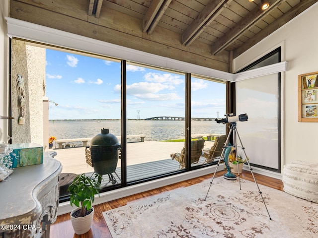 sunroom / solarium featuring wooden ceiling, a water view, and lofted ceiling with beams