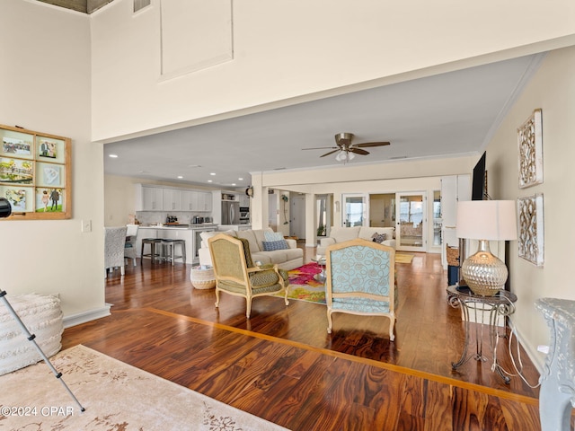 living room featuring ornamental molding, dark wood-type flooring, and ceiling fan