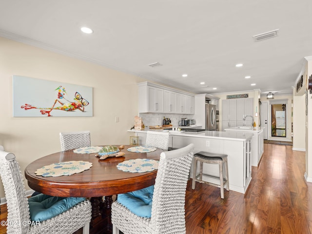 dining space with dark hardwood / wood-style floors, crown molding, and sink