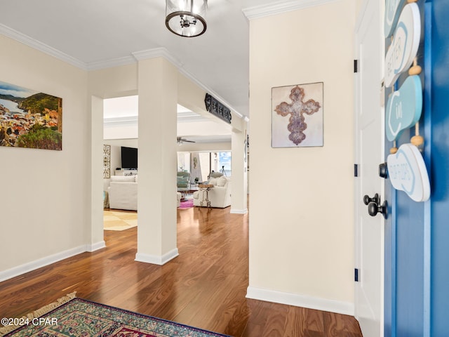 corridor with ornamental molding, hardwood / wood-style flooring, and a notable chandelier