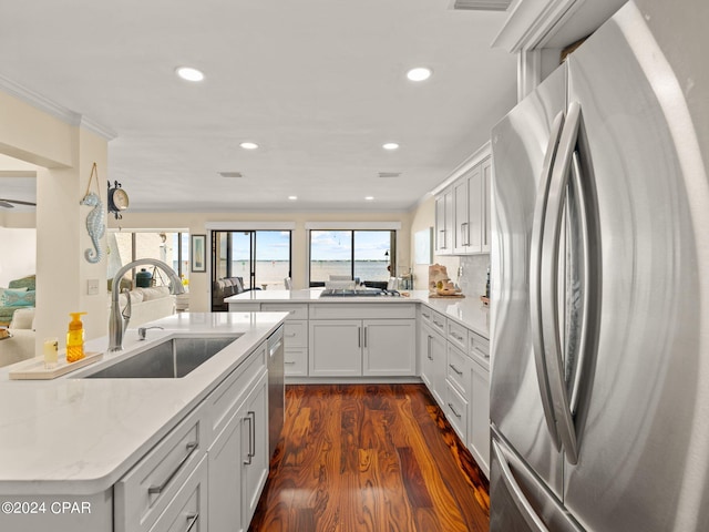 kitchen with light stone countertops, dark hardwood / wood-style flooring, stainless steel refrigerator, sink, and kitchen peninsula