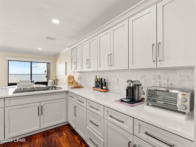 kitchen with white cabinetry, tasteful backsplash, stainless steel gas stovetop, kitchen peninsula, and dark hardwood / wood-style floors