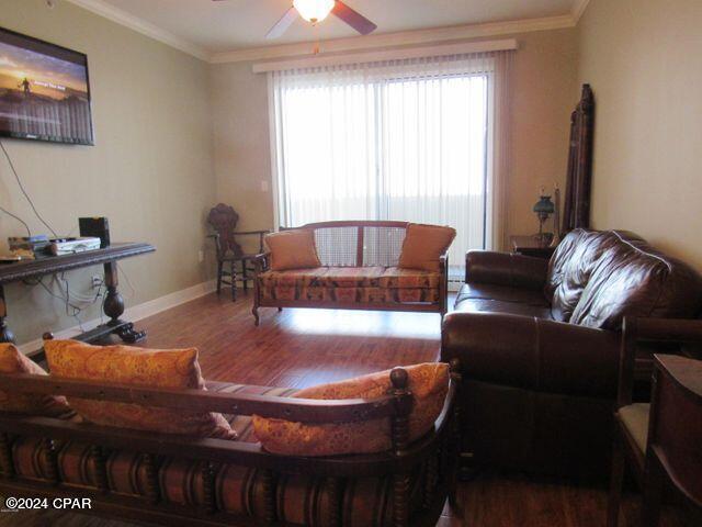 living room featuring wood-type flooring, ceiling fan, and crown molding