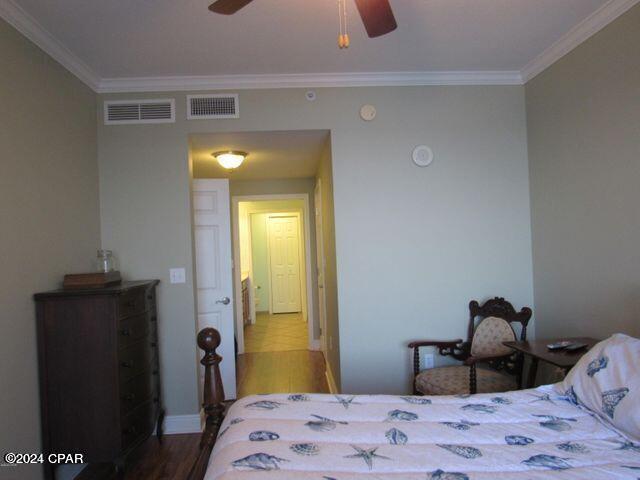 bedroom featuring crown molding, wood-type flooring, and ceiling fan