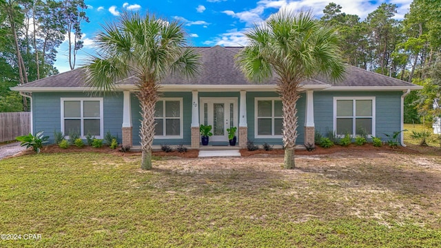 view of front of house featuring a front yard, covered porch, and roof with shingles