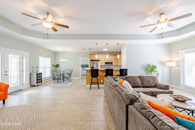 living room with ceiling fan with notable chandelier, baseboards, and light tile patterned floors