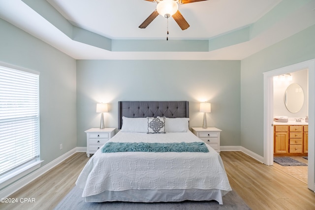 bedroom featuring light wood-style flooring, baseboards, and ensuite bathroom