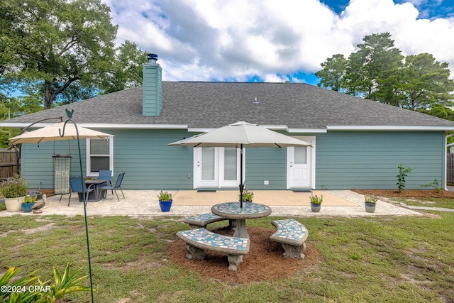 rear view of house with a lawn and a patio