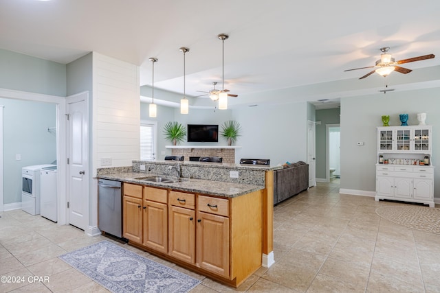 kitchen featuring a sink, open floor plan, stainless steel dishwasher, light stone countertops, and washing machine and clothes dryer