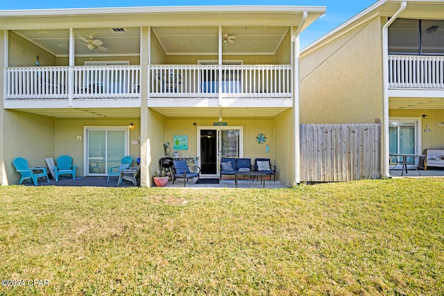 rear view of house with ceiling fan, a yard, and a patio area