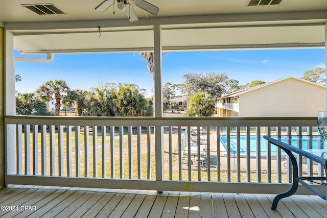 wooden terrace featuring a lawn, ceiling fan, and a community pool