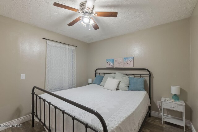 bedroom with a textured ceiling, dark wood-type flooring, and ceiling fan