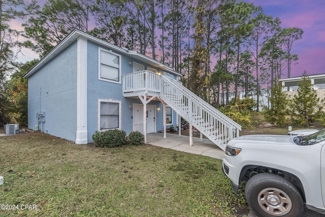 view of front of home featuring a lawn and central AC unit