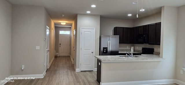 kitchen featuring light hardwood / wood-style flooring, black appliances, kitchen peninsula, and sink