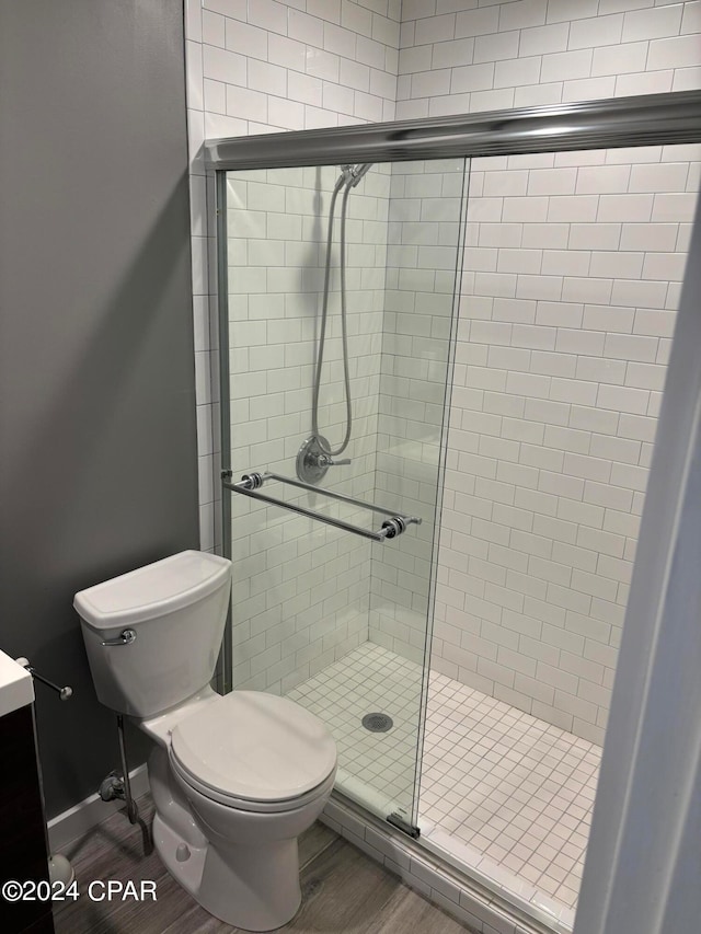 bathroom featuring hardwood / wood-style floors, vanity, toilet, and a shower with shower door