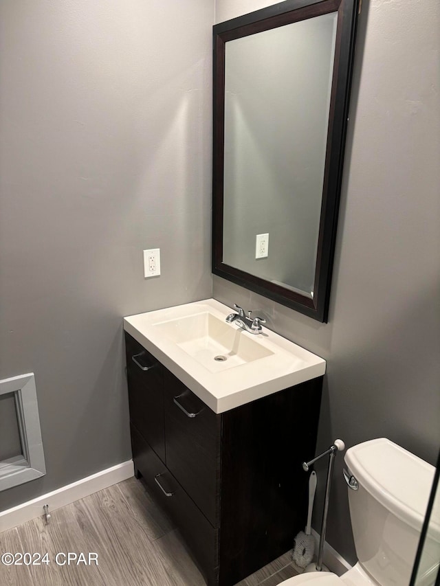 bathroom featuring wood-type flooring, vanity, and toilet