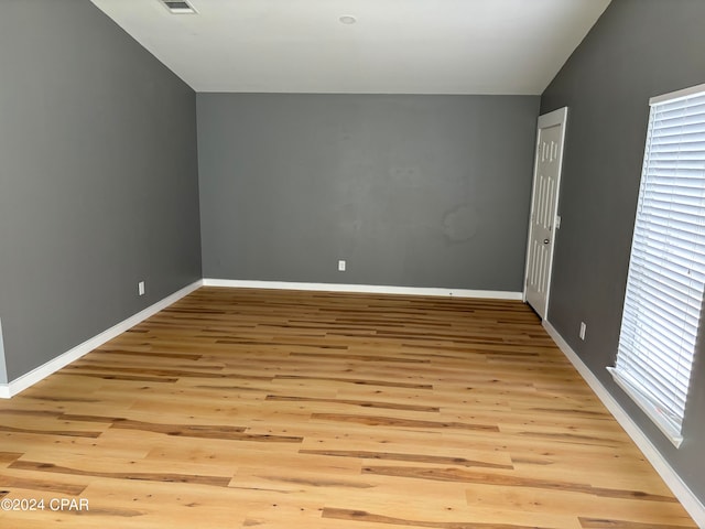 unfurnished room featuring light hardwood / wood-style floors and vaulted ceiling