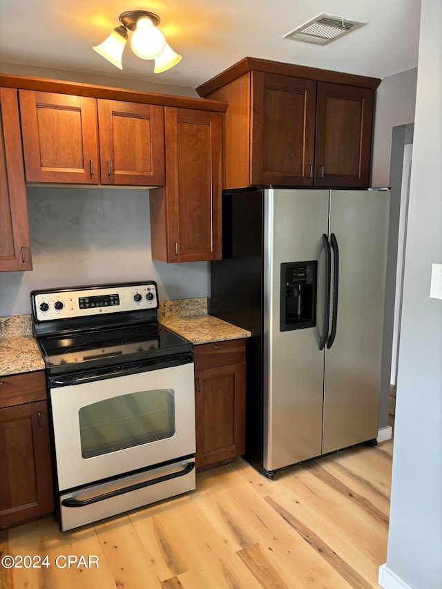 kitchen with light stone countertops, ceiling fan, range with electric cooktop, light hardwood / wood-style flooring, and stainless steel fridge with ice dispenser