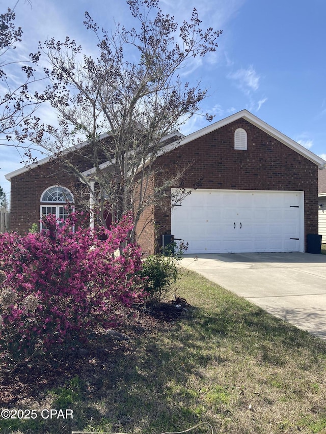 ranch-style home with driveway, an attached garage, and brick siding