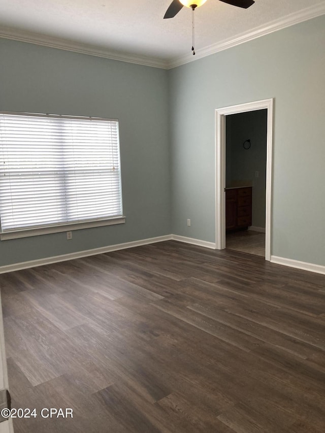 empty room with baseboards, ornamental molding, ceiling fan, and dark wood-style flooring