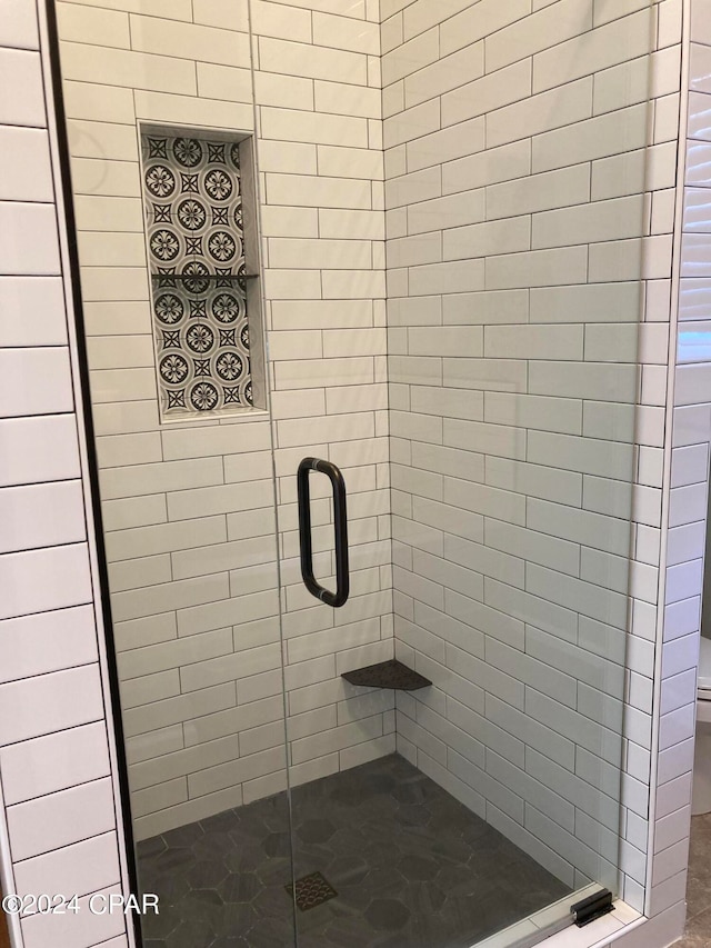 bathroom featuring toilet and a shower with door