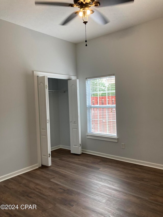 unfurnished bedroom with dark wood-type flooring, a closet, and ceiling fan