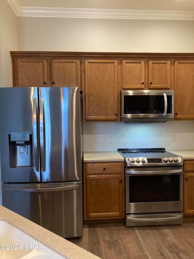 kitchen featuring ornamental molding, stainless steel appliances, dark wood-type flooring, and tasteful backsplash