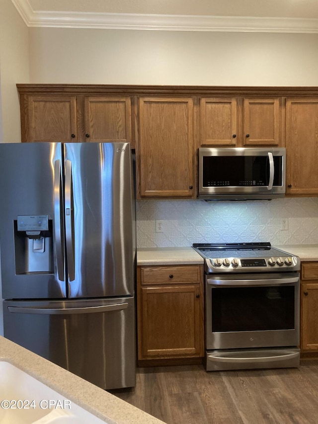 kitchen featuring stainless steel appliances, dark wood finished floors, light countertops, and crown molding