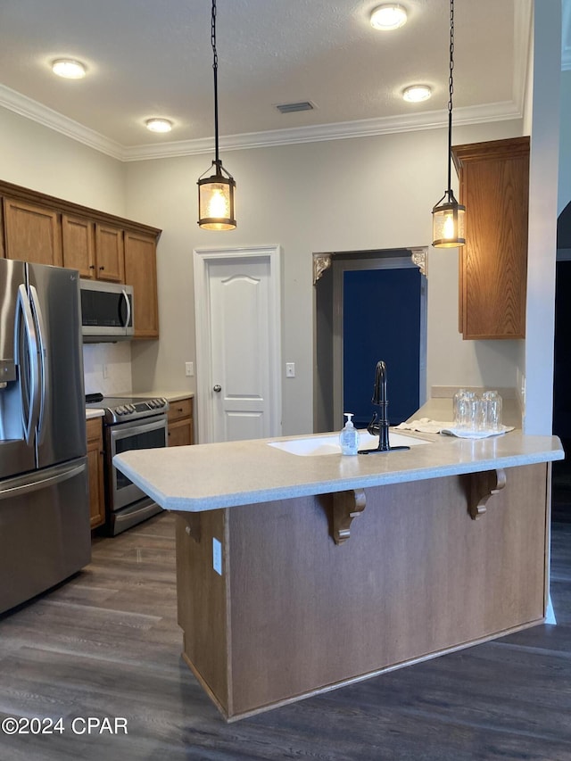 kitchen featuring dark wood finished floors, stainless steel appliances, visible vents, brown cabinetry, and a kitchen breakfast bar