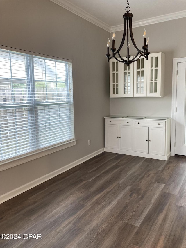 unfurnished dining area with baseboards, ornamental molding, dark wood finished floors, and a notable chandelier