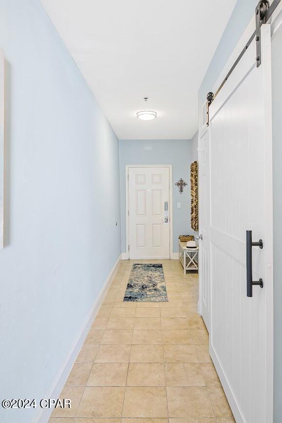 entryway with a barn door, baseboards, and light tile patterned flooring