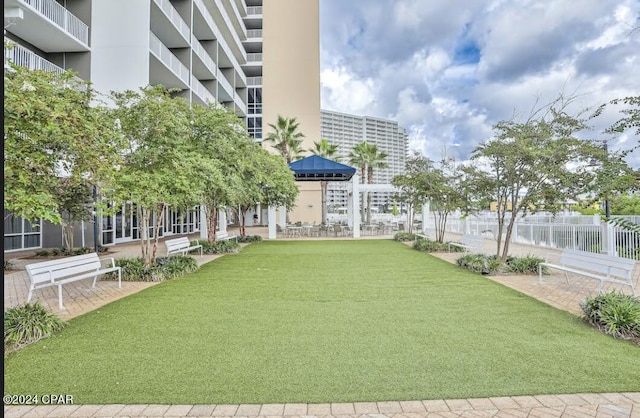 view of community featuring fence and a yard