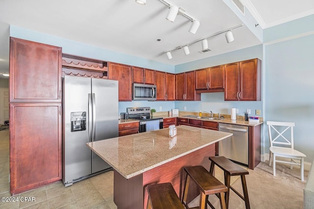 kitchen with stainless steel appliances, visible vents, a kitchen island, light stone countertops, and a kitchen bar