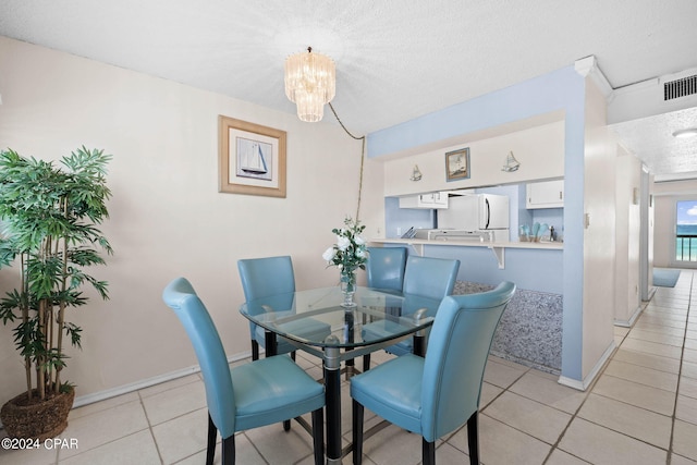 tiled dining room with an inviting chandelier and a textured ceiling