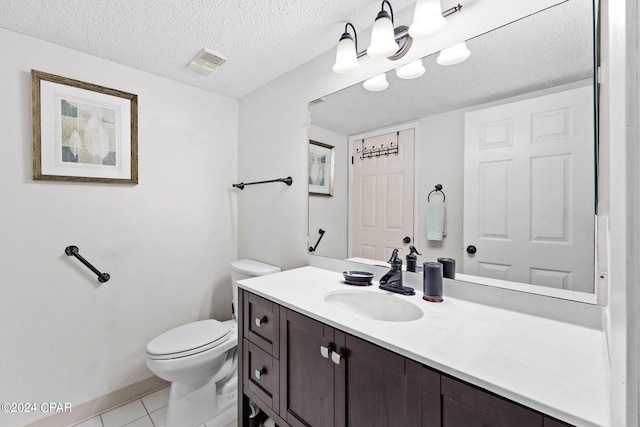 bathroom with a textured ceiling, vanity, toilet, and tile patterned floors