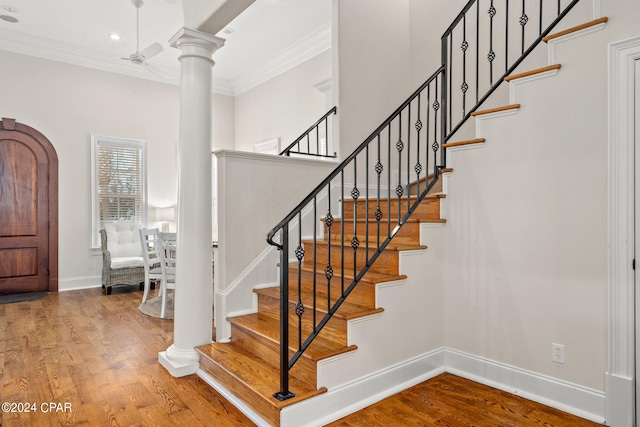 foyer featuring wood-type flooring, crown molding, and ornate columns