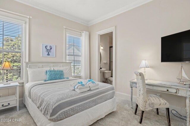 carpeted bedroom with ornamental molding, ensuite bathroom, and multiple windows