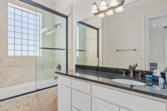 bathroom featuring vanity, a shower with shower door, and ornamental molding