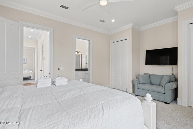 bedroom featuring light carpet, ensuite bath, ceiling fan, and crown molding