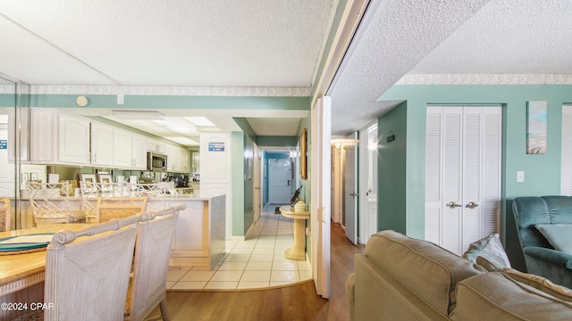 kitchen with white cabinetry, a textured ceiling, and light wood-type flooring