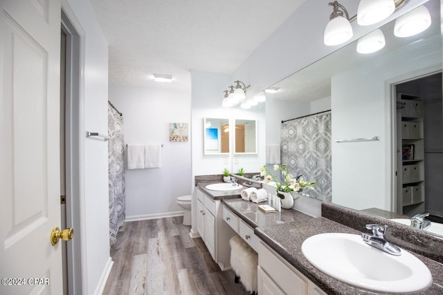 bathroom featuring toilet, vanity, hardwood / wood-style flooring, a textured ceiling, and a shower with shower curtain