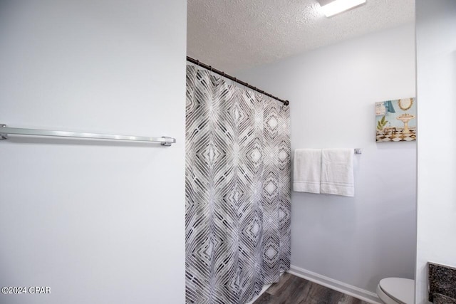 bathroom with toilet, wood-type flooring, curtained shower, and a textured ceiling