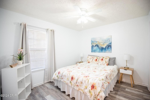 bedroom with a textured ceiling, ceiling fan, and hardwood / wood-style flooring