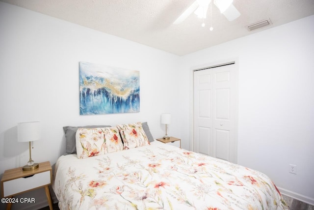 bedroom featuring a textured ceiling, wood-type flooring, ceiling fan, and a closet