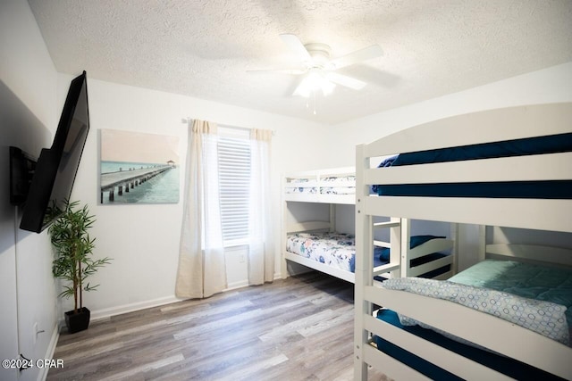 bedroom with a textured ceiling, ceiling fan, and hardwood / wood-style floors