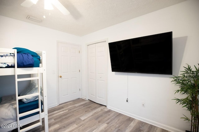 bedroom with a textured ceiling, ceiling fan, and light hardwood / wood-style floors