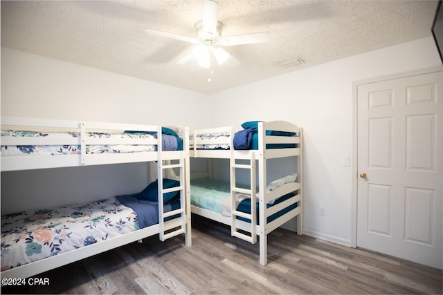 bedroom with a textured ceiling, ceiling fan, and hardwood / wood-style flooring