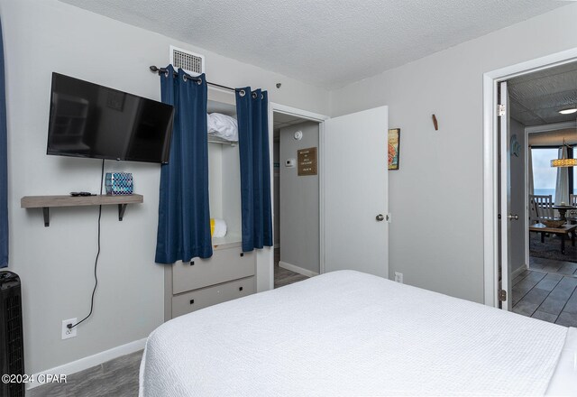 bedroom with a textured ceiling and dark hardwood / wood-style flooring